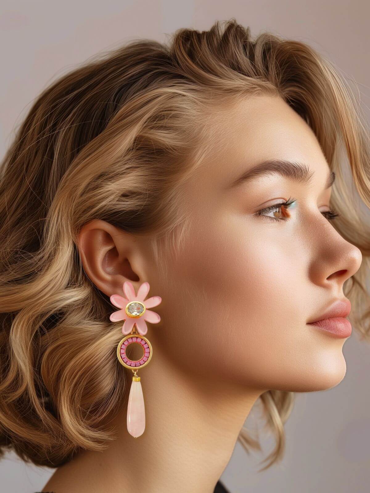 Vrouw met roze statement oorbel met agaat, messing en kristallen details, van het Maud Roze sieradenassortiment