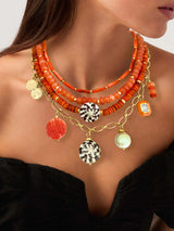 Vrouw draagt Mave oranje schelp ketting met gouden accenten en kralen, uit de Classic Collection, perfect voor een vleugje zee-betovering.