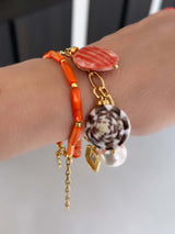 Mays oranje armband met schelpkralen, gouden details en prachtige parels in onze Classic Collection, gedragen rond een pols.